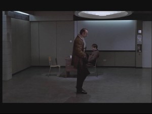 Interviewroom Note the vastness of the interview room and the incongruously old fashioned nature of the desk that Brannen is sitting at.